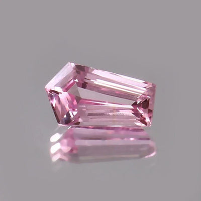 Pink Padparadscha Sapphire gemstone on a gray background