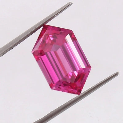 Ceylon Pink Sapphire gemstone held between tweezers on a light gray background
