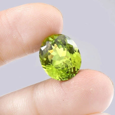 Green Peridot gemstone held between fingers against a neutral background