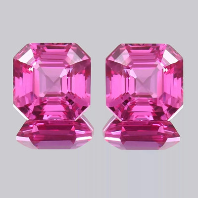 pair Ceylon Pink Sapphire gemstones with a hexagonal cut on a gray background