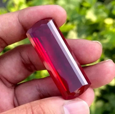 Red huge burma Ruby held in a hand with a blurred green background
