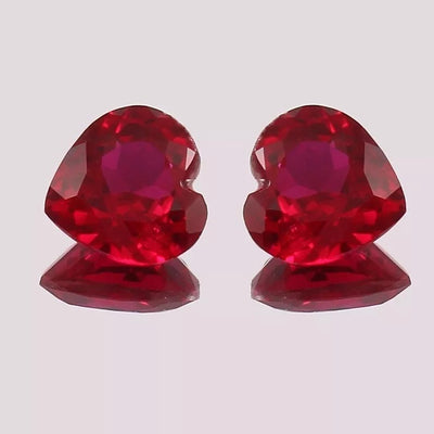 Pair Blood Red Mozambique Ruby heart-shaped objects on a light gray background