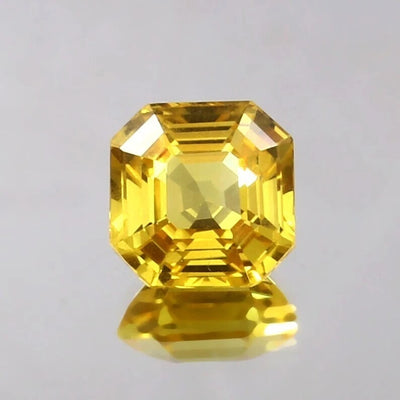 Faceted Yellow Sapphire gemstone on a gray background