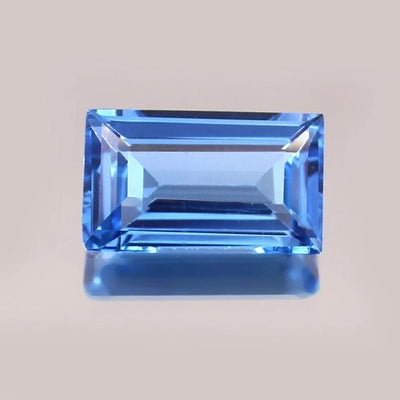 Brazilian Aquamarine Baguette Cut gemstone on a beige background