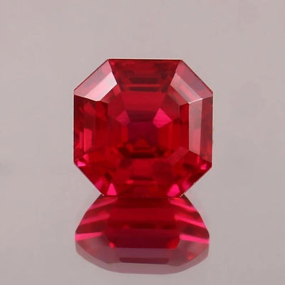 Faceted Pigeon Blood Ruby gemstone on a gray background