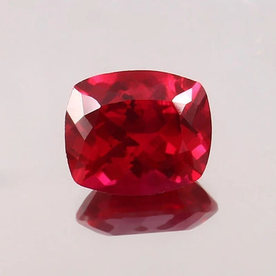 Cushion-shaped Pigeon Blood Ruby gemstone on a light gray background