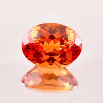 Faceted Fanta Orange Sapphire gemstone on a light gray background