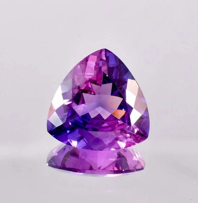 Trillion-shaped Bi-Color Purple Sapphire gemstone on a light gray background