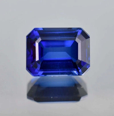 Faceted Royal Blue Sapphire gemstone on a light gray background