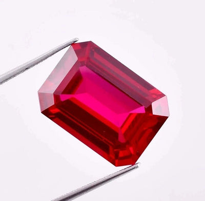 Pigeon Blood Ruby gemstone held by tweezers on a white background