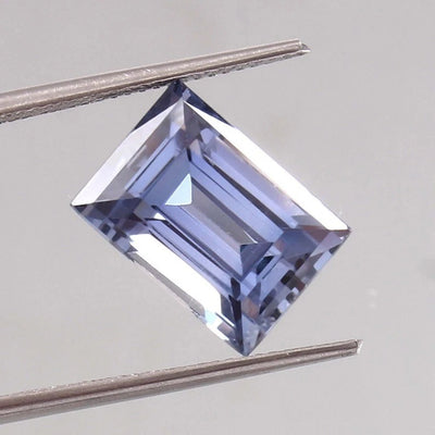 Ceylon Blue Sapphire – Baguette Cut gemstone held by tweezers on a light gray background