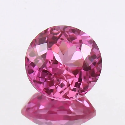 Pink Sapphire gemstone on a reflective surface with a light purple background