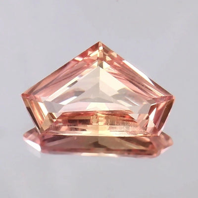 Padparadscha Sapphire gemstone on a light gray background