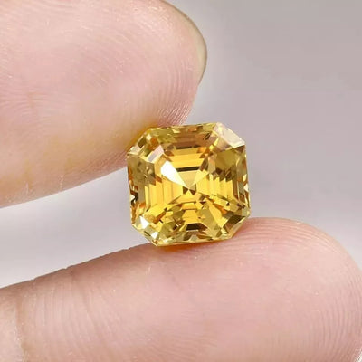 Ceylon Yellow Sapphire gemstone held between fingers against a neutral background
