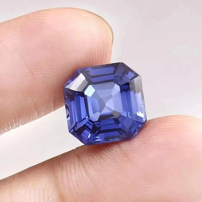 Royal Blue Sapphire gemstone held between fingers against a neutral background