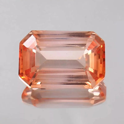 Bi-Color Padparadscha gemstone on a gray background