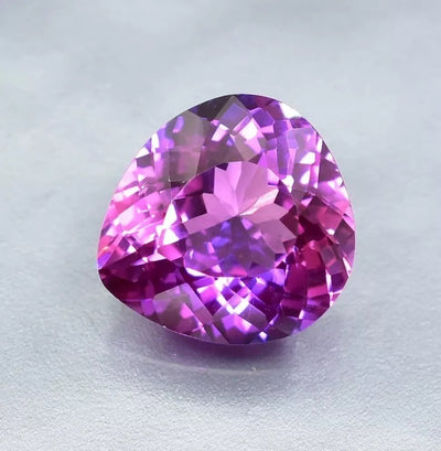 Purple Blue Sapphire gemstone on a light gray background