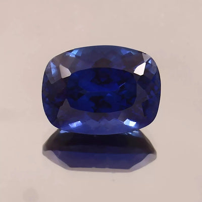 Faceted Blue Sapphire gemstone on a beige background