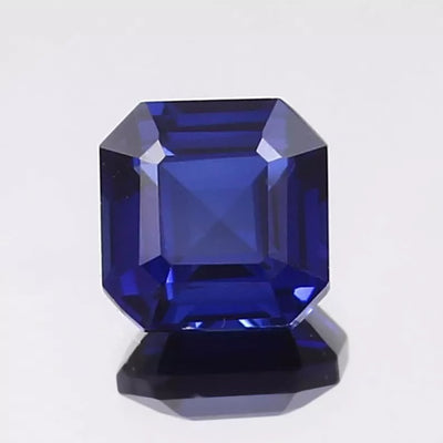 Faceted Cornflower blue sapphire gemstone on a light gray background