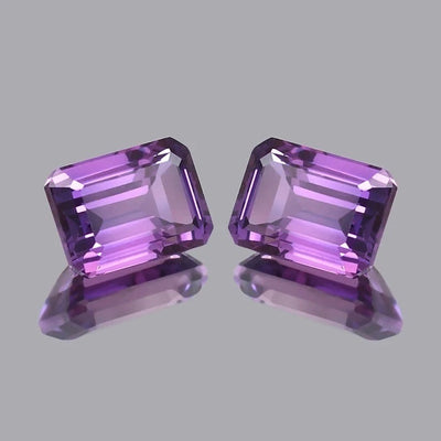 Pair Ceylon Purple Sapphire gemstones on a gray background