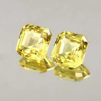Yellow Ceylon Sapphire Pair gemstones on a reflective gray surface