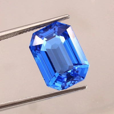 Blue sapphire sri lanka gemstone held by tweezers on a neutral background